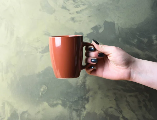 brown tea or coffee cup in hand on textured background