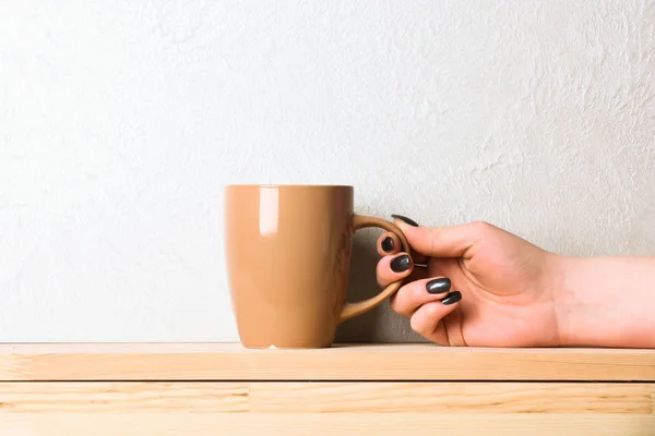 Beige tea or coffee cup in hand on white background — Stock Photo, Image