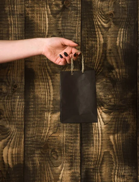 Sac à provisions noir à la main féminine sur fond en bois — Photo
