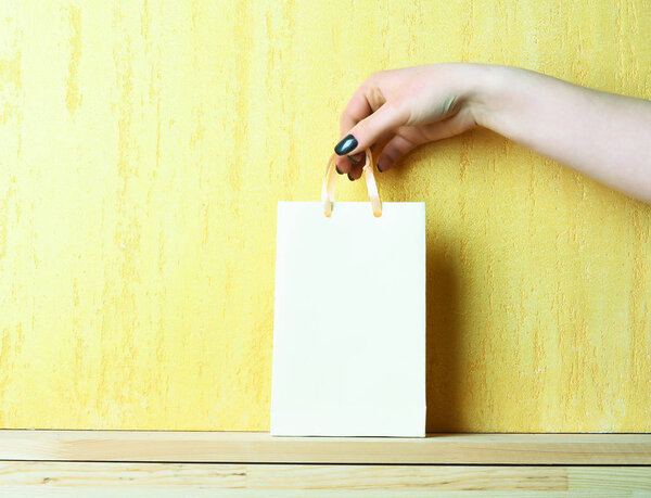 легкий пакет для покупок в женской руке на желтой стене
