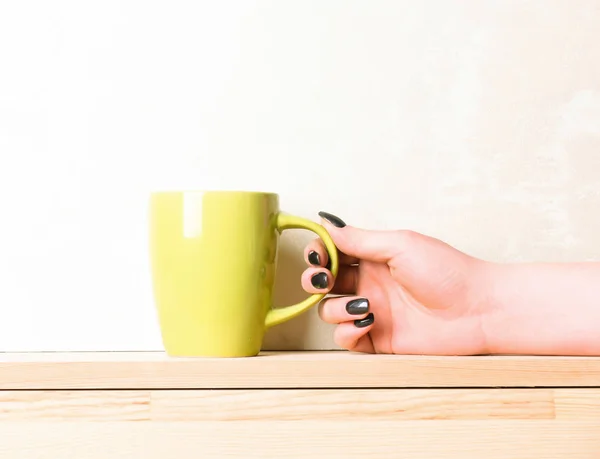 yellow tea or coffee cup in hand on white background