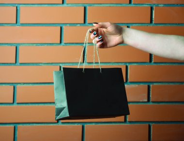 tuğla duvar kadın elinde siyah alışveriş çantası