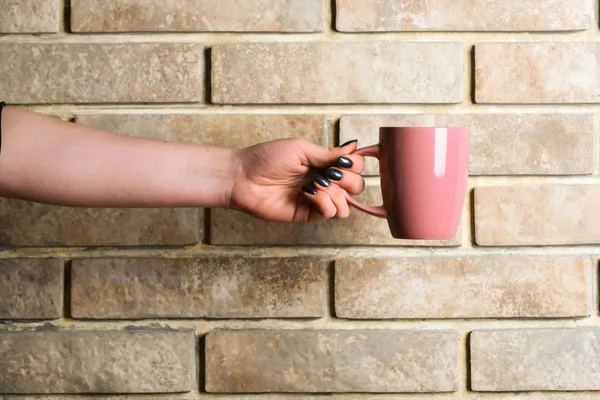 Chá rosa ou xícara de café na mão na parede de tijolo — Fotografia de Stock