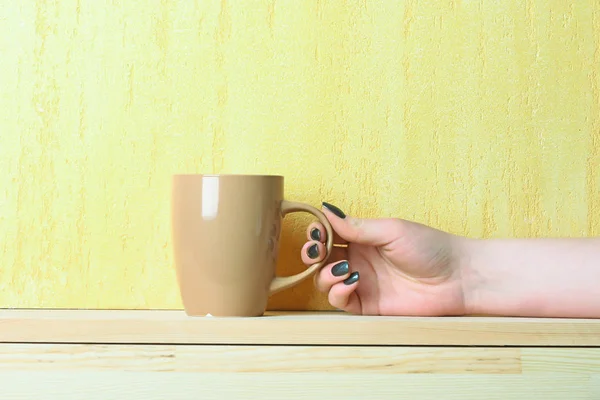 Bézs tea vagy csésze kávé a kezében sárga háttér — Stock Fotó