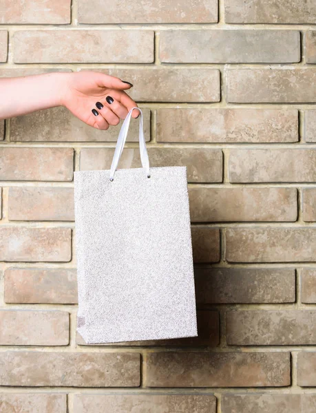 Saco de compras branco na mão feminina na parede de tijolo — Fotografia de Stock