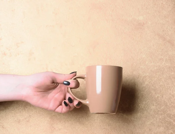 Chá bege ou xícara de café na mão sobre fundo texturizado — Fotografia de Stock