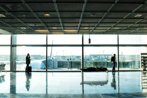 People with luggage waiting hall of airport at window glass — Stock Photo, Image