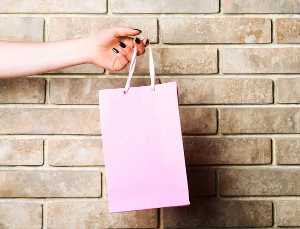 벽돌 벽에 여성 손에 빛 핑크 쇼핑백 — 스톡 사진