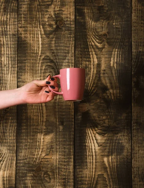 Chá rosa ou xícara de café na mão sobre fundo de madeira — Fotografia de Stock
