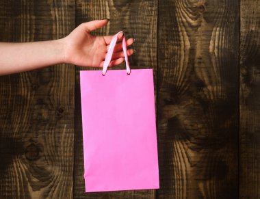 ahşap arka plan üzerinde kadın elinde pembe alışveriş çantası