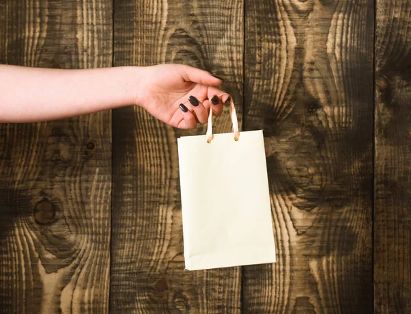 나무 배경에 여성 손에 흰색 쇼핑백 — 스톡 사진