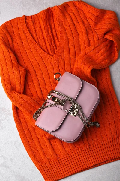 small womans leather pink bag with orange sweater