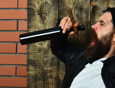 Sakallı, Kafkas hippisi elinde şişe, puro içiyor.