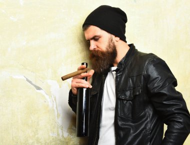 Sakallı, Kafkas hippisi elinde şişe, puro içiyor.