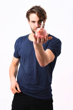 Beyaz seksi genç maço elinde pembe domuz kumbarası tutuyor.