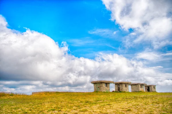 Kleine steenachtige lege huizen op het groene gras en bewolkte hemel — Stockfoto