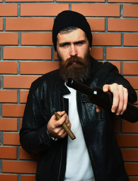 Vousatý brutální kavkazský hipster držící láhev a kouřící doutník — Stock fotografie