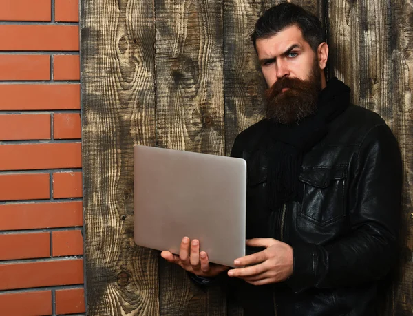 Bearded brutal caucasian hipster holding tablet and laptop — Stock Photo, Image