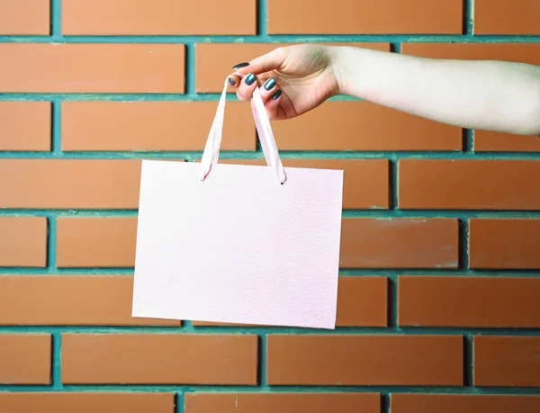 Sac à provisions rose clair à la main féminine sur mur de briques — Photo