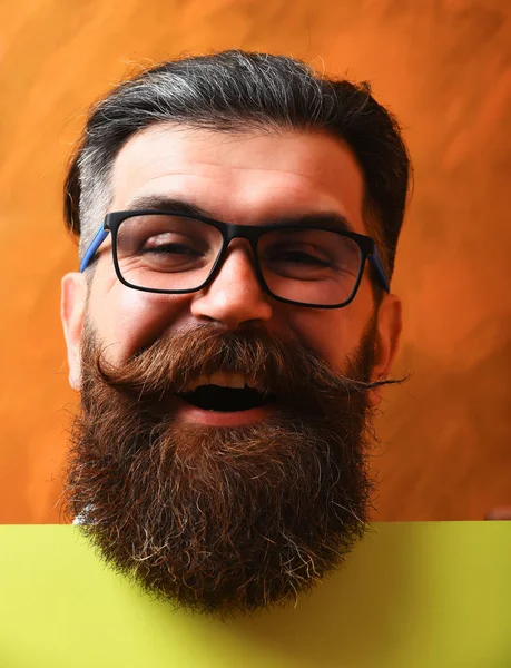 Бородатый мужчина со счастливым лицом в очках на оранжевом фоне — стоковое фото