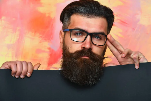 Бородатый человек с серьезным лицом в очках на красочном фоне — стоковое фото