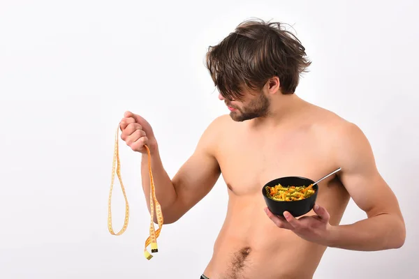Caucasian macho holding black bowl with pasta and measuring tape — Stock Photo, Image