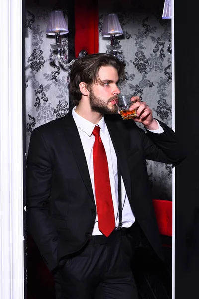 Vousatý muž, obchodník v obleku, červená kravata drží sklenici whisky — Stock fotografie
