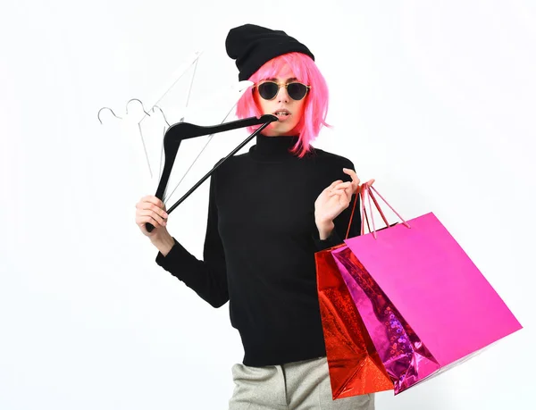 Fashionable sexy girl in pink wig holding package with hangers — Stock Photo, Image