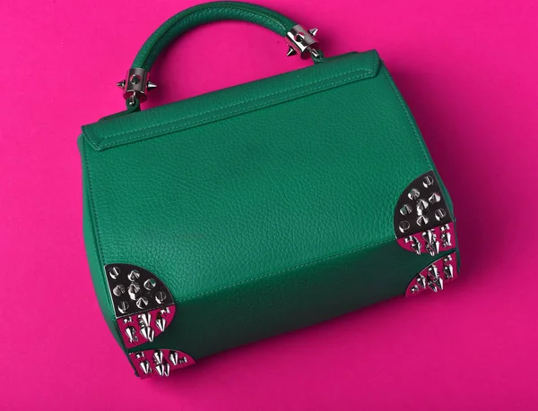 small womans leather green bag with metallic spikes on pink