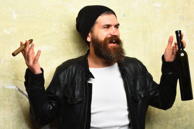 Sakallı, Kafkas hippisi elinde şişe, puro içiyor.