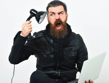 Sakallı, beyaz tenli hippi dizüstü bilgisayarla oturuyor.