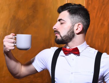 Elinde çay tutan sakallı adam, ciddi yüzlü kahve.