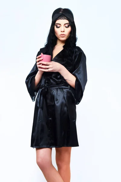 Сексуальна дівчина позує в чорному шовковому халаті з чашкою — стокове фото