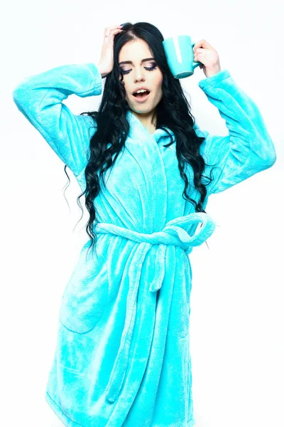 Turkuaz kadife bornozla fincanla poz veren seksi kız.