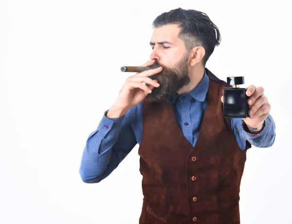 Hombre barbudo fumar cigarro con cara seria, la celebración de perfume —  Fotos de Stock