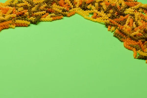 Барвисті макарони фузілі на зеленому фоні — стокове фото