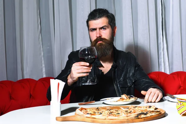 Człowiek z brodą je pizzę nożem i widelcem. — Zdjęcie stockowe