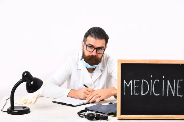 Kafkas sakallı doktor masada "Medicine" yazısıyla oturuyor. — Stok fotoğraf