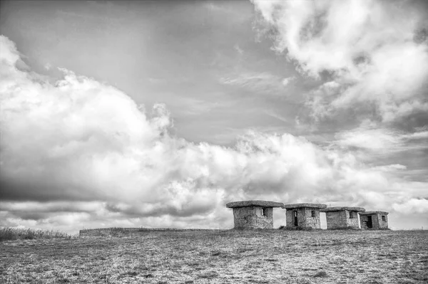 Pequeñas casas vacías pedregosas sobre hierba y cielo nublado —  Fotos de Stock