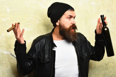 Sakallı, Kafkas hippisi elinde şişe, puro içiyor.