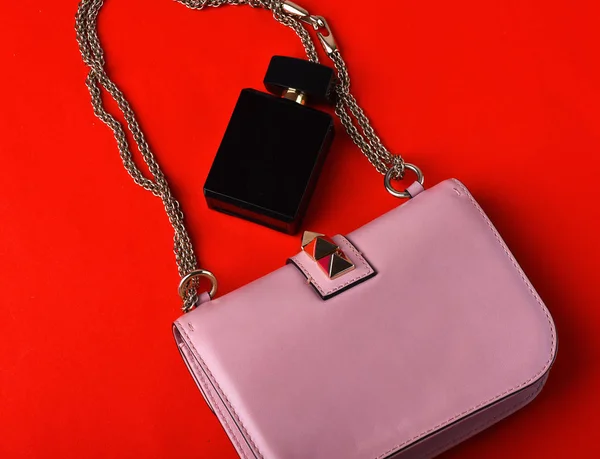 small womans leather pink bag with metallic spikes, chain, perfume