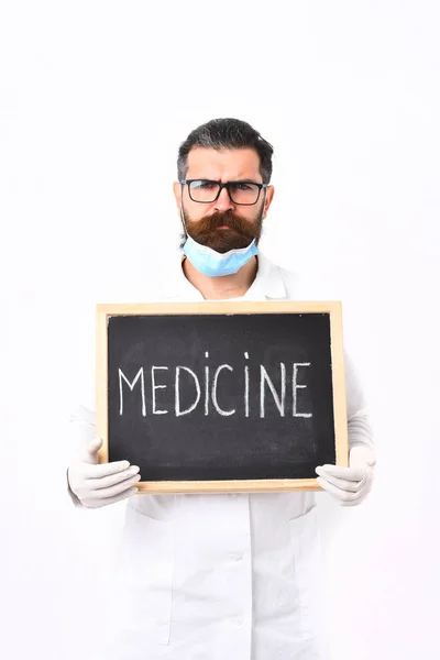 Médico caucasiano barbudo segurando seringa e papelão com inscrição em Medicina — Fotografia de Stock