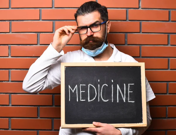 Brutalny, biały lekarz trzymający deskę z napisem "Medycyna" — Zdjęcie stockowe