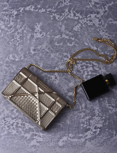 Kleine dames gemetalliseerde zilver zak met metalen ketting in de buurt van parfum — Stockfoto