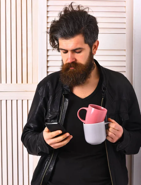 Brutala kaukasiska hipster innehav kopp eller mugg och mobiltelefon — Stockfoto