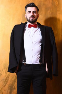 Stüdyo duvarında ciddi bir yüzü olan sakallı bir adam.