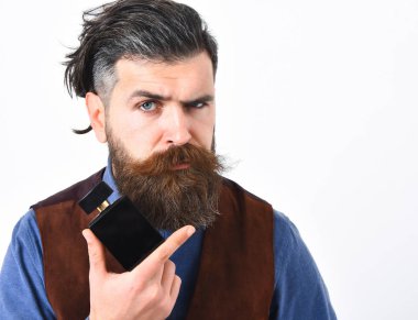 Sakallı adam ciddi bir parfüm tutuyor.