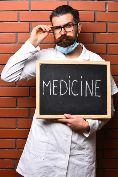Brutalny, biały lekarz trzymający deskę z napisem "Medycyna" — Zdjęcie stockowe