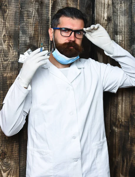 Bearded brutal caucasian doctor or postgraduate student holding pills