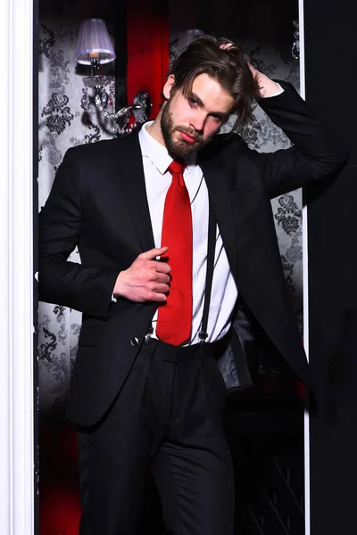 Skäggig man, affärsman i kostym och röd slips mot tapet — Stockfoto